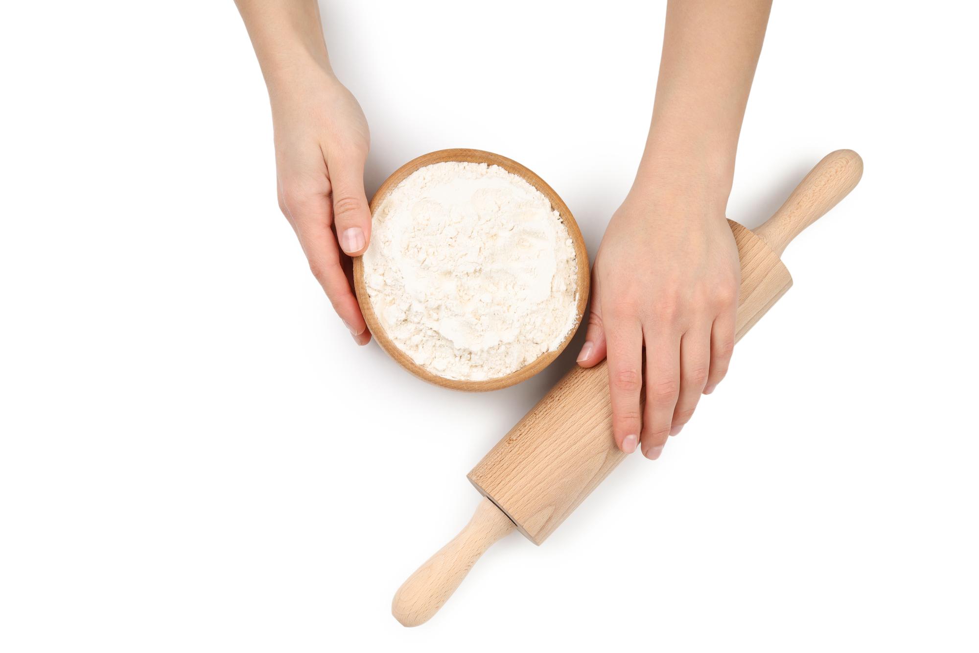 Hands shaping dough on floured board